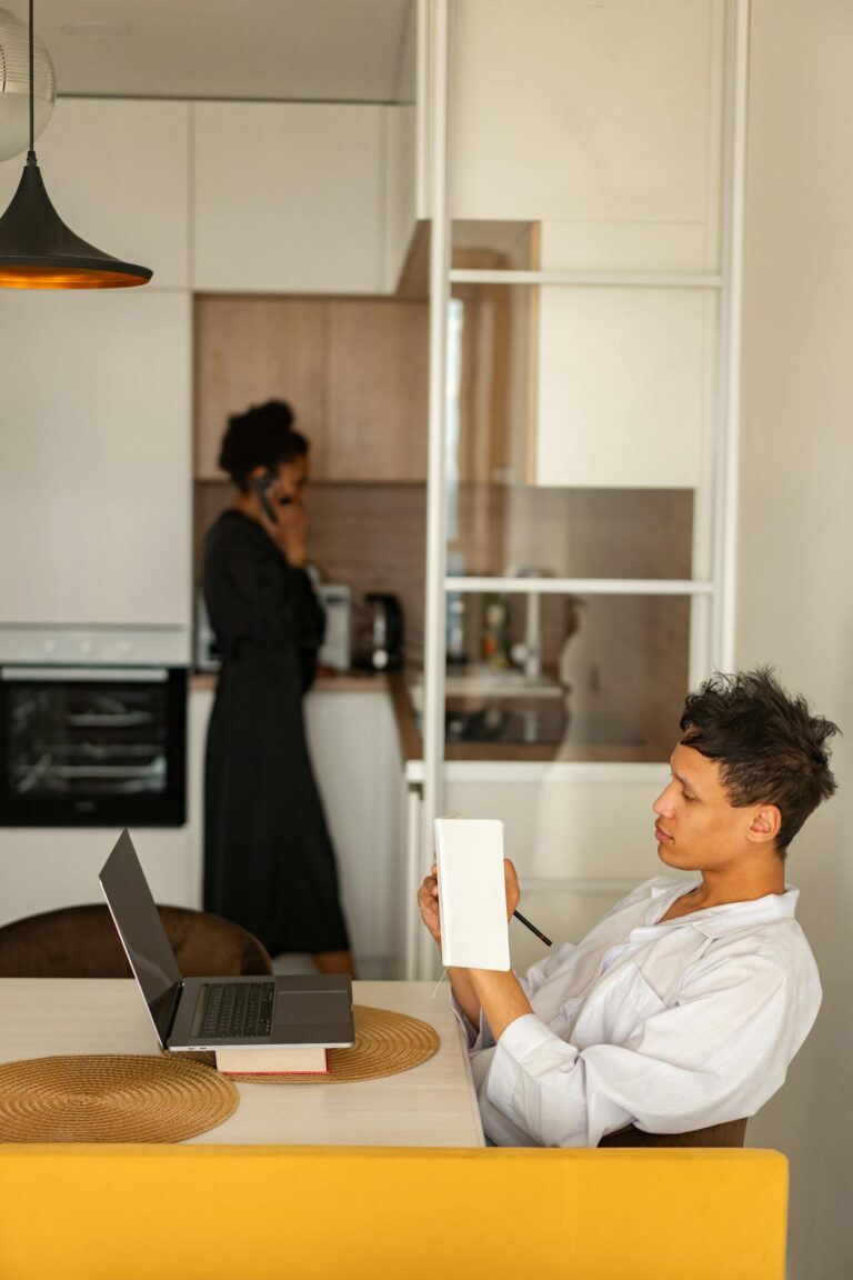 Young professional engaged in remote work in a stylish home kitchen setting, promoting a modern lifestyle.